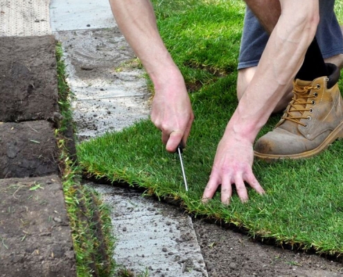 Person measuring and cutting turf